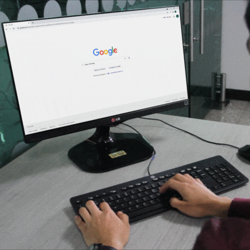 Persona tecleando en computador y texto apareciendo en espacio de búsqueda de google.